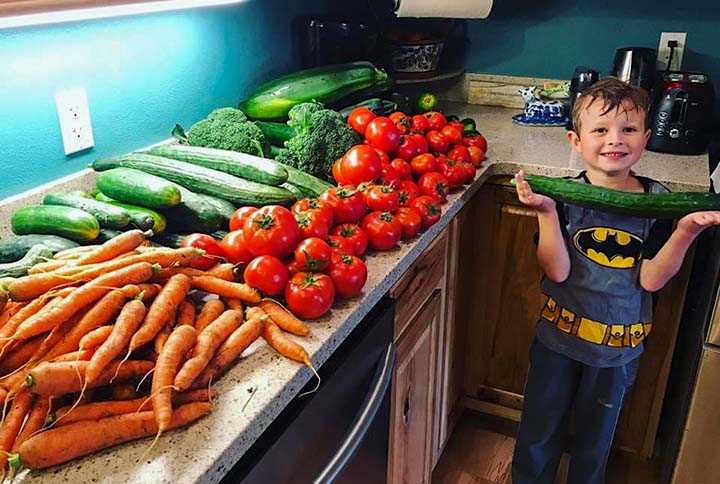 boy posing with lots of fresh vegatables